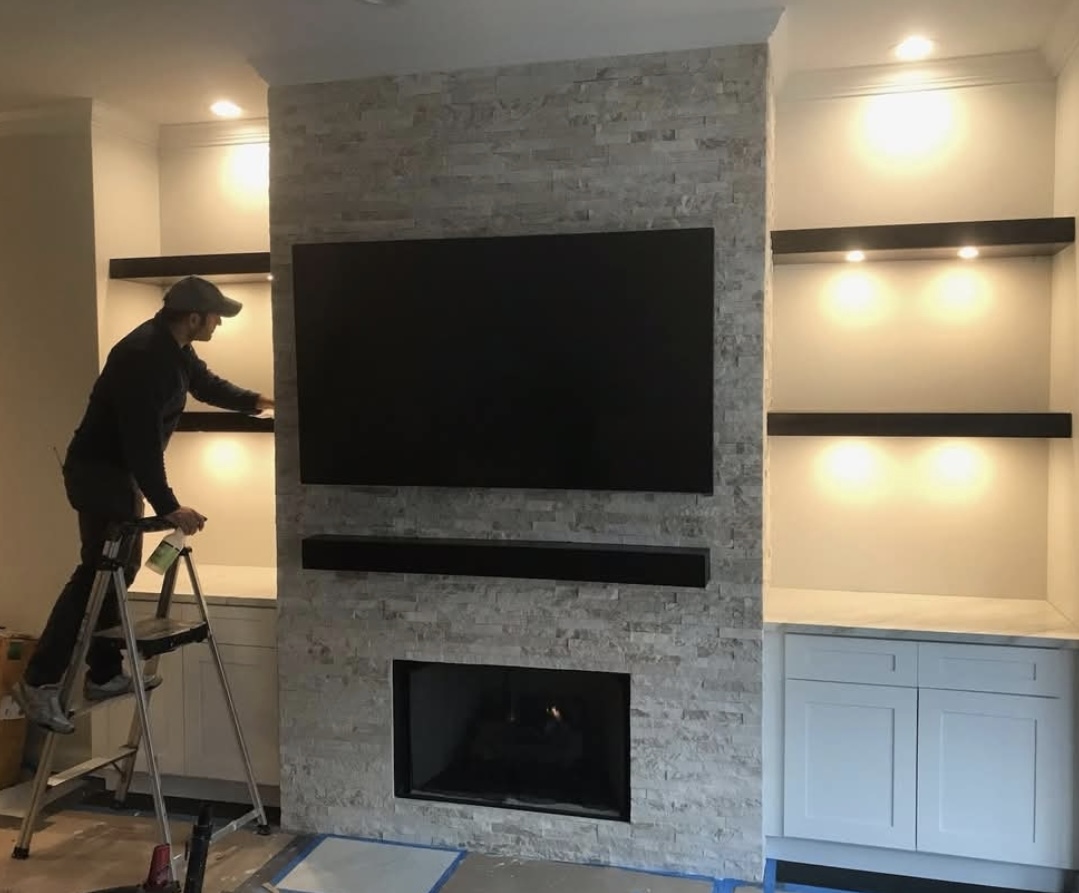 GH1 team member installing a stacked-stone fireplace and built-in media wall